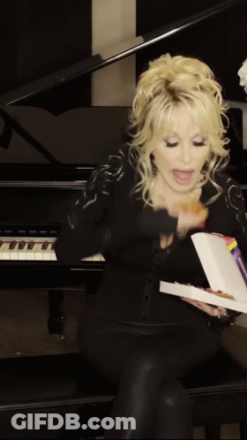 A Woman Is Sitting In Front Of A Piano Holding A Box Of Pizza GIF