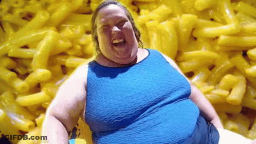 A Woman Is Sitting In Front Of A Pile Of Macaroni And Cheese . GIF
