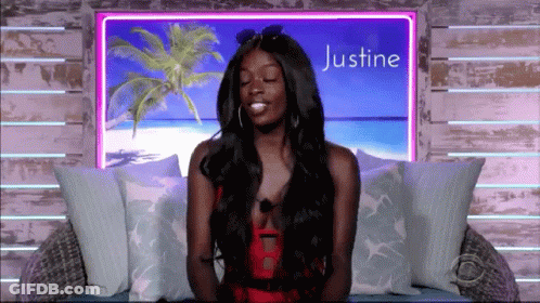 A Woman Is Sitting In Front Of A Sign That Says Justine On It GIF