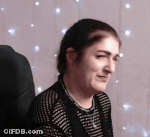 A Woman Is Sitting In Front Of A String Of Lights GIF