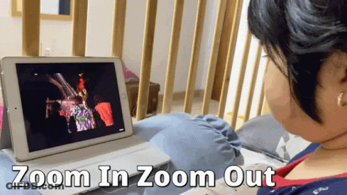 A Woman Is Sitting In Front Of A Tablet That Says Zoom In Zoom Out On The Bottom GIF