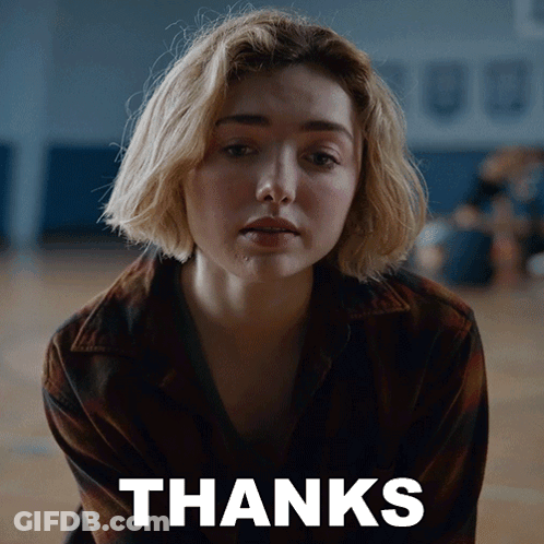A Woman Is Sitting In Front Of A Thanks Sign GIF