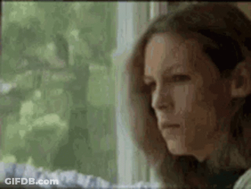 A Woman Is Sitting In Front Of A Window Looking Out . GIF