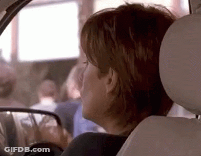A Woman Is Sitting In The Back Seat Of A Car . GIF