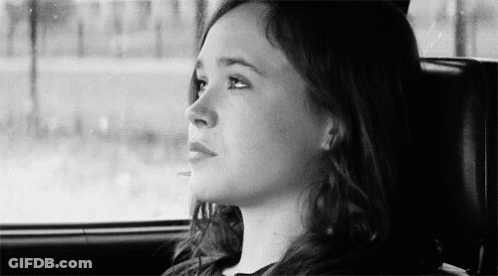A Woman Is Sitting In The Back Seat Of A Car And Looking Out The Window . GIF