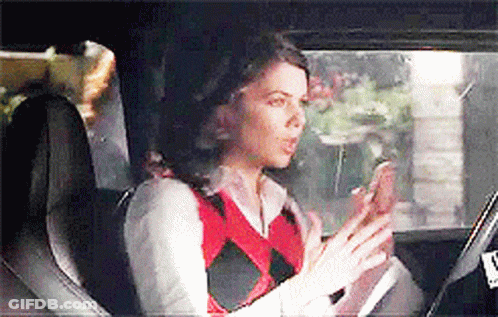 A Woman Is Sitting In The Back Seat Of A Car Looking At Her Phone . GIF