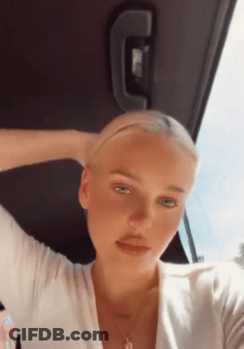 A Woman Is Sitting In The Back Seat Of A Car With Her Hand In Her Hair GIF
