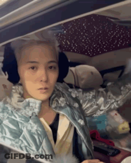 A Woman Is Sitting In The Driver 'S Seat Of A Car Wearing Ear Muffs . GIF
