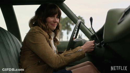 A Woman Is Sitting In The Driver 'S Seat Of A Car With The Netflix Logo On The Dashboard GIF