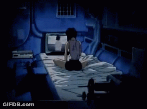 A Woman Is Sitting On A Bed In A Dark Room Watching A Television . GIF