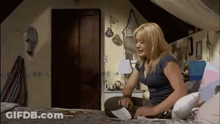A Woman Is Sitting On A Bed In An Attic Room Looking At A Piece Of Paper . GIF