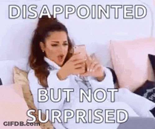 A Woman Is Sitting On A Bed Looking At Her Phone And Says Disappointed But Not Surprised . GIF