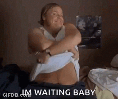 A Woman Is Sitting On A Bed Taking Off Her Shirt And Says `` Im Waiting Baby '' . GIF