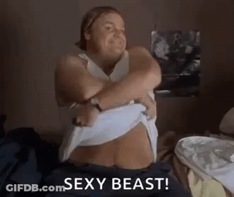 A Woman Is Sitting On A Bed Taking Off Her Shirt And Says `` Sexy Beast '' . GIF