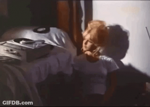 A Woman Is Sitting On A Bed Talking On A Cell Phone . GIF