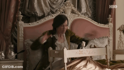 A Woman Is Sitting On A Bed With A Tray In Front Of Her That Says Hbo On The Bottom GIF