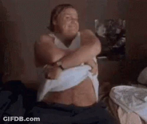 A Woman Is Sitting On A Bed With Her Arms Around Her Chest . GIF