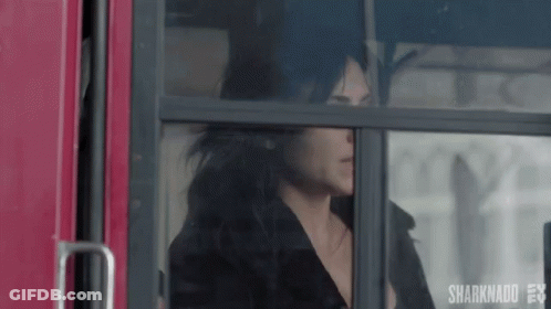 A Woman Is Sitting On A Bus Looking Out The Window . GIF