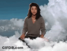 A Woman Is Sitting On A Cloud With A Blue Sky Behind Her GIF
