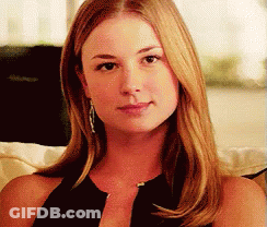 A Woman Is Sitting On A Couch And Looking At The Camera . GIF