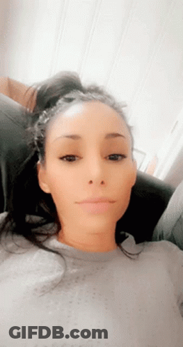 A Woman Is Sitting On A Couch And Making A Funny Face GIF