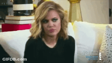A Woman Is Sitting On A Couch And Making A Funny Face GIF