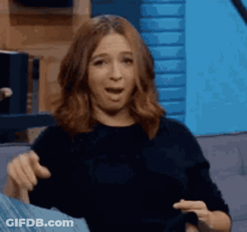 A Woman Is Sitting On A Couch And Pointing At Something . GIF