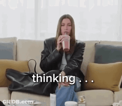 A Woman Is Sitting On A Couch Drinking A Smoothie And The Word Thinking Is On The Screen GIF