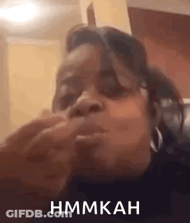 A Woman Is Sitting On A Couch Eating A Sandwich And Making A Funny Face . GIF