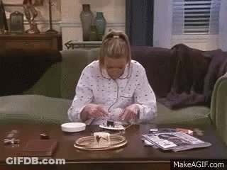 A Woman Is Sitting On A Couch Eating Cake On A Table . GIF