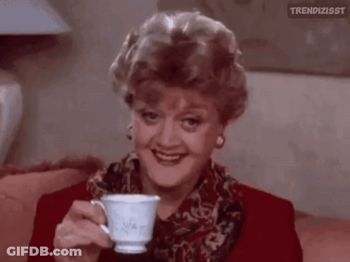 A Woman Is Sitting On A Couch Holding A Cup Of Tea . GIF