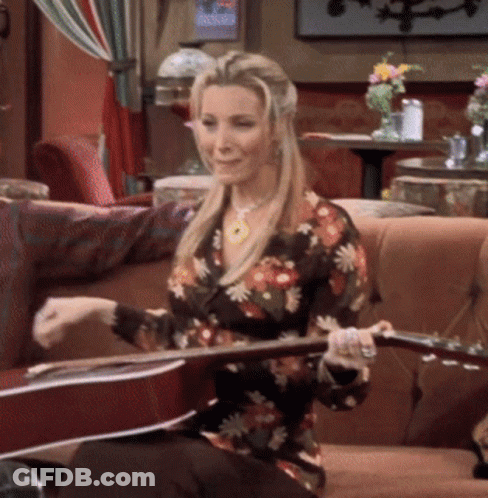 A Woman Is Sitting On A Couch Holding A Guitar GIF