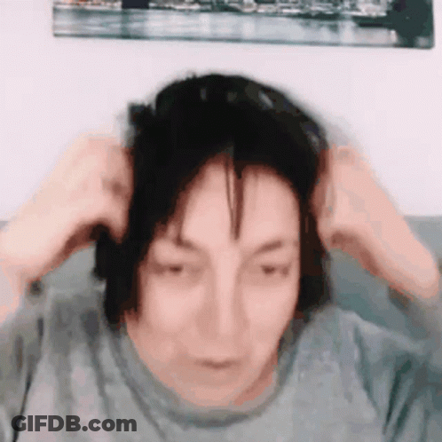 A Woman Is Sitting On A Couch Holding Her Hair In Her Hands . GIF