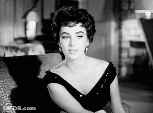 A Woman Is Sitting On A Couch In A Black And White Photo . GIF