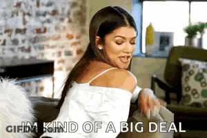 A Woman Is Sitting On A Couch In A Living Room Holding A Book And Saying `` Im Kind Of A Big Deal '' GIF