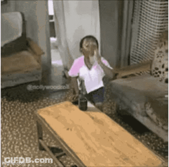 A Woman Is Sitting On A Couch In A Living Room Holding A Glass Of Water . GIF