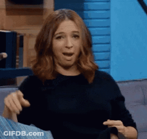 A Woman Is Sitting On A Couch Making A Funny Face . GIF
