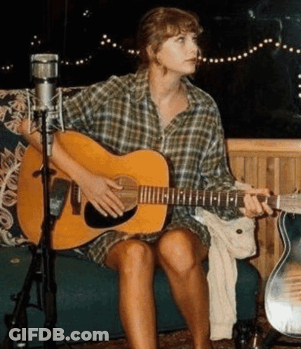 A Woman Is Sitting On A Couch Playing A Guitar . GIF