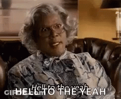 A Woman Is Sitting On A Couch With A Cigarette In Her Mouth And Says `` Hell To The Yeah '' . GIF