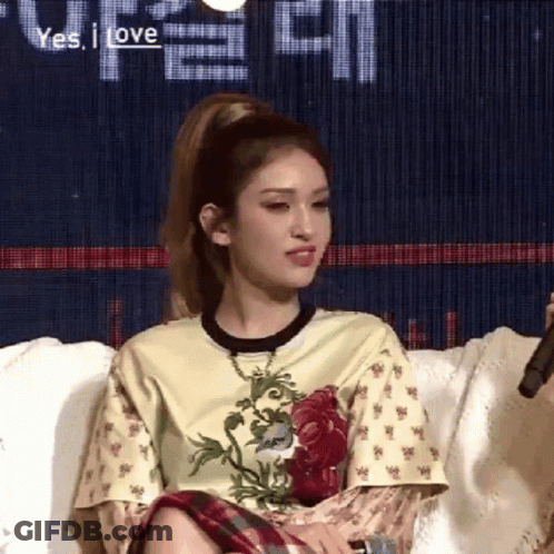 A Woman Is Sitting On A Couch With A Microphone In Her Hand And A Ponytail . GIF