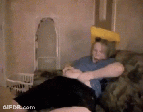 A Woman Is Sitting On A Couch With A Pillow On Her Head And A Yellow Pillow On Her Head . GIF