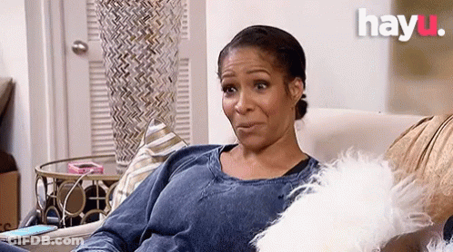 A Woman Is Sitting On A Couch With A White Pillow And A Phone . GIF