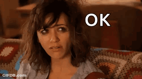 A Woman Is Sitting On A Couch With Her Hair Blowing In The Wind And The Words `` Ok Hot Mess '' Above Her . GIF