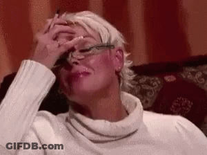 A Woman Is Sitting On A Couch With Her Hand On Her Forehead . GIF