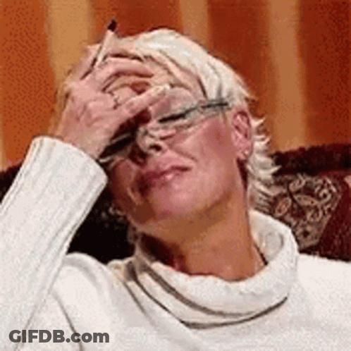 A Woman Is Sitting On A Couch With Her Hand On Her Forehead . GIF