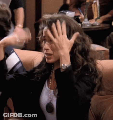 A Woman Is Sitting On A Couch With Her Hand On Her Head GIF