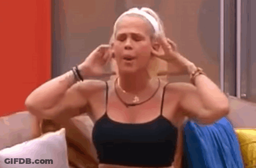 A Woman Is Sitting On A Couch With Her Hands On Her Ears . GIF