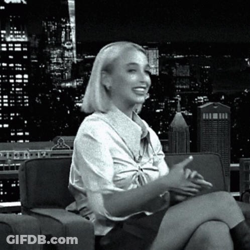 A Woman Is Sitting On A Couch With Her Legs Crossed GIF