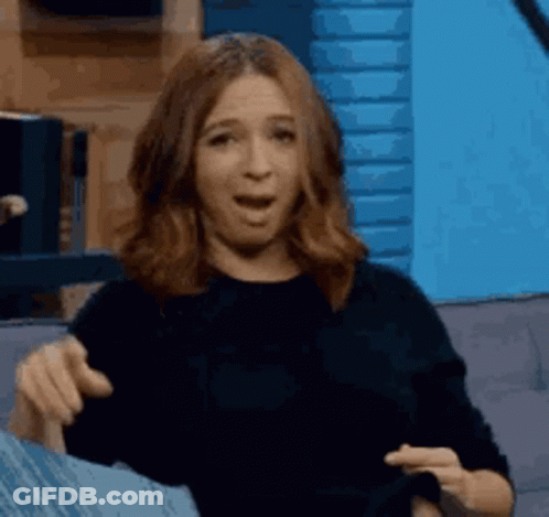 A Woman Is Sitting On A Couch With Her Mouth Open And Making A Funny Face . GIF