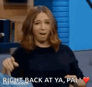 A Woman Is Sitting On A Couch With Her Mouth Open And Pointing At Something . GIF